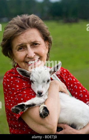 Senior woman holding baby goat sur le terrain Banque D'Images