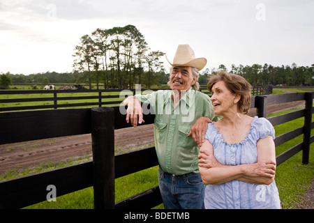 Senior couple standing on ranch près de parler de clôture Banque D'Images