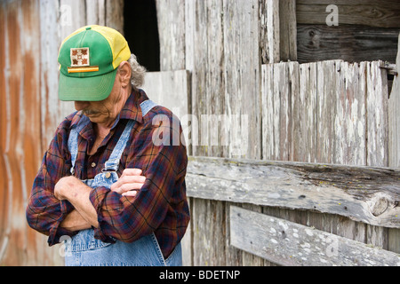 Senior man standing near barn à capuchon vert tiré vers le bas sur le visage Banque D'Images