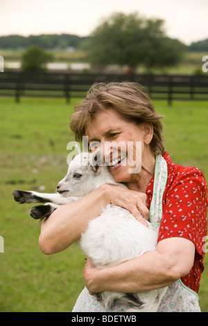 Senior woman holding baby goat sur le terrain Banque D'Images