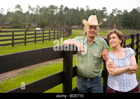 Senior couple standing on ranch près de clôture Banque D'Images