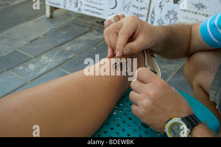 Man applying tatouage au henné à la jambe de femme Banque D'Images