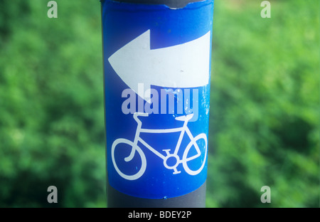 Close up of stick-sur bleu et blanc signe sur pole avec le feuillage derrière avec location d'icône et de la flèche indiquant la route Banque D'Images