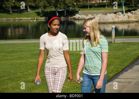 La diversité ethnique mélange racialement mixtes deux filles accrocher à traîner ensemble et hispanique Hispanic junior high pour marcher autour du parc trottoir. M. © Myrleen Pearson Banque D'Images