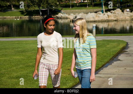 Deux jeunes filles 11-13 ans accrocher à traîner ensemble et Hispaniques Caucasian girls Marche à pied d'interpolations de Tween trottoir jeune fille gens Monsieur © Myrleen Pearson Banque D'Images