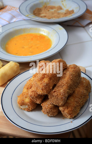 Un tas de croquettes de pomme de terre fraîchement préparés, avec un couple en attente d'enrobage et de plaques et d'oeufs chapelure derrière Banque D'Images