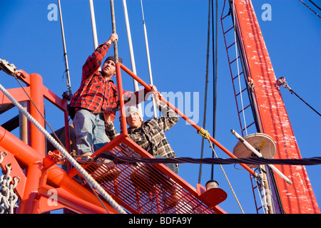 Low angle view de pêcheurs en chemises à carreaux travaillant sur bateau de pêche Banque D'Images