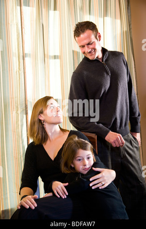 Famille de trois qui pose pour portrait en face de la fenêtre Banque D'Images