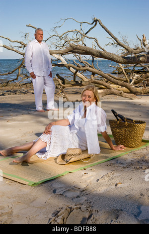 Middle-aged couple relaxing on beach ensemble Banque D'Images