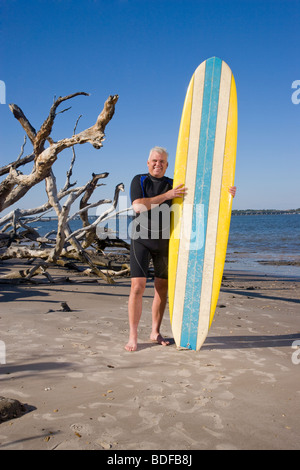 Homme d'âge moyen en combinaison sur beach with surfboard Banque D'Images