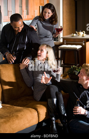 Multi-ethnic couples having drinks ensemble dans la salle de séjour Banque D'Images