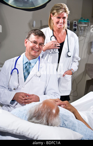 Doctors with patient in hospital room Banque D'Images