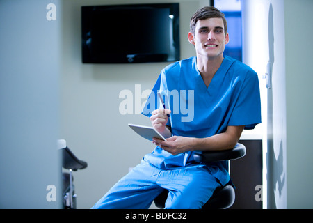 Portrait of young doctor in scrubs holding pad et stylet Banque D'Images