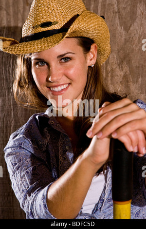 Portrait of young woman standing in horse stable et fourche Banque D'Images