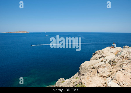 Un hors-bord solitaire qui passe dans la vaste mer bleue au large des falaises de Fornells sur l'île Baléares de Minorque Espagne Banque D'Images