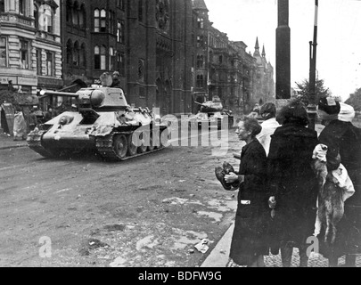 Des chars russes entrez les ruines d'un Berlin en 1945 vu par un groupe de femmes d'appréhension Banque D'Images