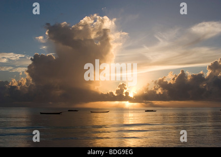 Volutes nuages à une aube aube sur plage de Paje, Zanzibar. Or spectaculaire les nuages se forment dans le ciel au-dessus de l'océan. Banque D'Images