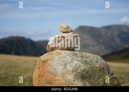 Gros plan de roches empilées sur un cairn sur Grey knotts, dans le Lake District Fells, Cumbria. Avec Haystacks et High Crag en arrière-plan Banque D'Images