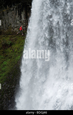 Une femme trail running derrière une cascade en Silver Falls State Park, Oregon, USA. Banque D'Images