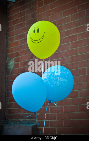 Visage souriant jaune marque ballons bleu entrée de la partie. Banque D'Images