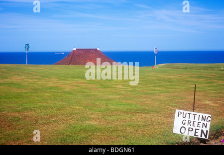 L'herbe éparse déserte avec amateur affiche un vert d'ouvrir avec mer bleue et un abri en bord de toit distance Banque D'Images