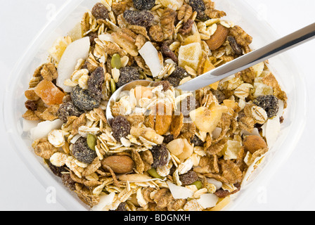 Fruit de plusieurs et l'écrou muesli avec cuillère en argent disposés dans la boîte en plastique et isolé sur fond blanc Banque D'Images