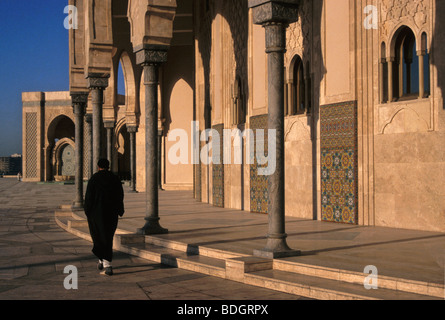 Homme avec des vêtements traditionnels de marcher le long de la mosquée au coucher du soleil à Casablanca - Maroc Banque D'Images