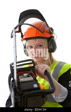 Les jeunes 20 ans blond woman wearing hard hat orange protège-oreilles et des pare-soleil vis vest holding à la tronçonneuse et smiling Banque D'Images