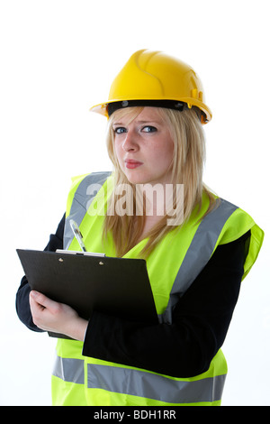 Les jeunes 20 ans blond woman wearing hard hat jaune Gilet haute visibilité et écrit sur un presse-papiers Banque D'Images