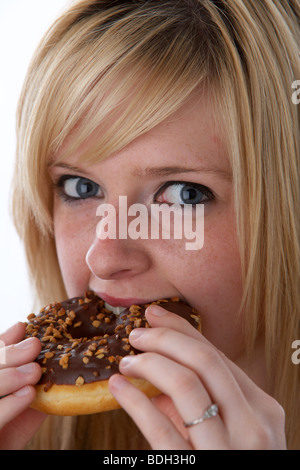 Les jeunes 20 ans blonde woman eating donut chocolat grand Banque D'Images