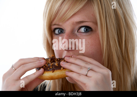 Les jeunes 20 ans blonde woman eating donut chocolat grand Banque D'Images