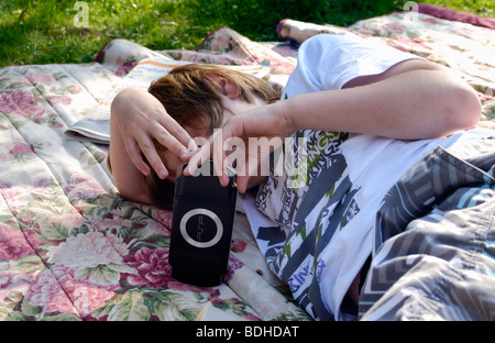 Jeune garçon allongé sur un tapis à l'extérieur de jouer sur un ordinateur psp Banque D'Images