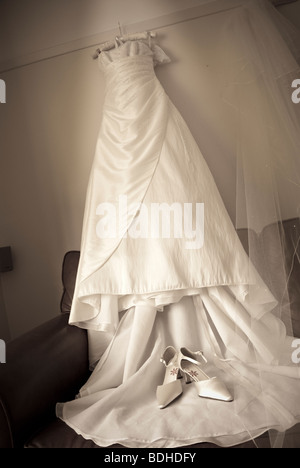 Robe nuptiale accroché au mur en attente de la mariée à se préparer Banque D'Images
