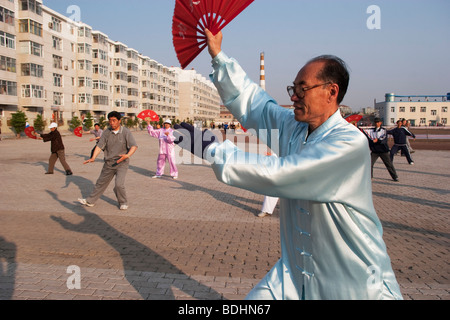 Tai Chi traditionnel chinois exécuter la danse du ventilateur sur une place à l'aube dans la ville de Hui, la province de Jilin, Chine. Banque D'Images