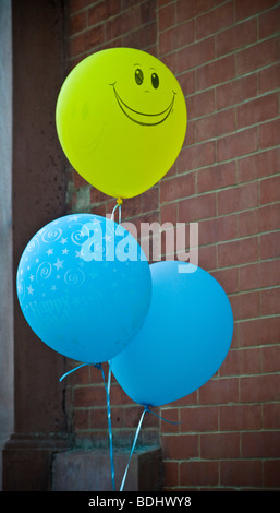 Visage souriant jaune marque ballons bleu entrée de la partie. Banque D'Images