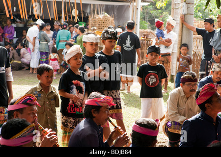 L'INDONÉSIE, Bali, Tirta Gangga, jeunes garçons regardant le gamelan orchestre jouer dans temple local cérémonie funéraire Banque D'Images