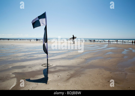 Un drapeau d'avertissement et de surfeur sur une plage soleil embrassé Banque D'Images