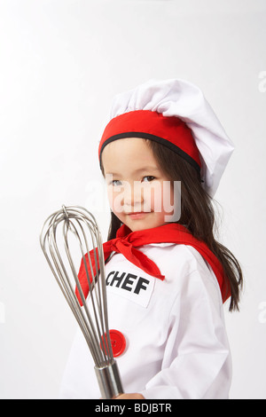 Petite fille habillé en chef Holding un fouet Banque D'Images