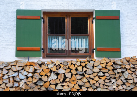 Bois de chauffage empilé en face de la fenêtre de l'ancienne ferme, Berchtesgaden, en Bavière, Allemagne Banque D'Images