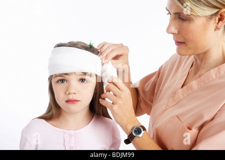 Nurse Wrapping bandage autour de la tête de la jeune fille Banque D'Images