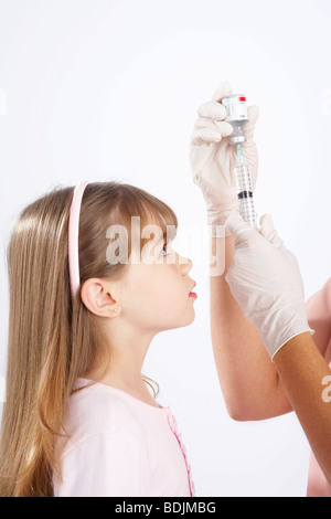 Petite fille en regardant l'Infirmière Préparer une aiguille Banque D'Images