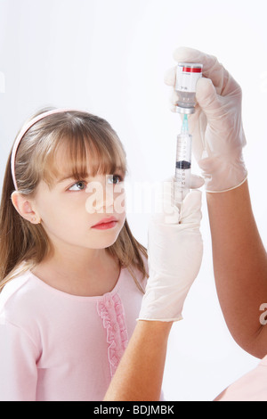 Petite fille en regardant l'Infirmière Préparer une aiguille Banque D'Images