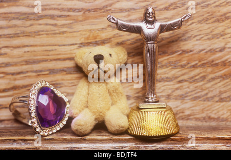 Jeune fille ou adolescente collection de bague cœur violet et petit ours en peluche et Jésus avec les bras tendus sur le rebord en bois Banque D'Images