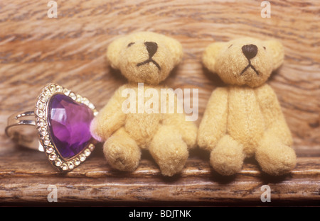 Jeune fille ou adolescente collection de bague cœur pourpre et deux petits nounours sur corniche en bois Banque D'Images