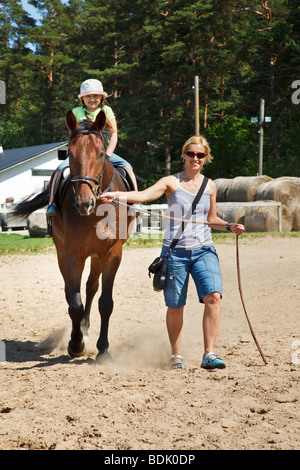 Petite fille souriante et équitation big horse Banque D'Images