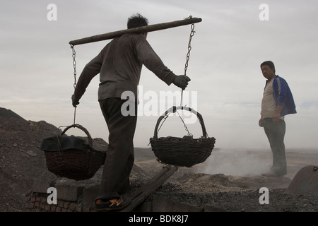 Domaine DU CHARBON WUDA, WU HAI, Mongolie intérieure, CHINE - AOÛT 2007 : Liang Yan Fa porte paniers de charbon tamisé pour faire du soufre. Banque D'Images