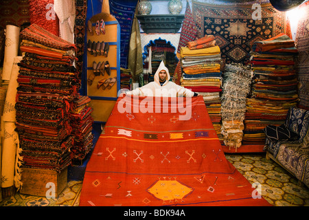 Chefchaouen, Maroc, Vendeur affichage tapis dans sa boutique de tapis. Banque D'Images