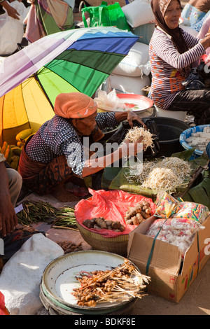 L'Indonésie, Lombok, Kuta, marché hebdomadaire vieille femme vendant des germes au kiosque de légumes Banque D'Images