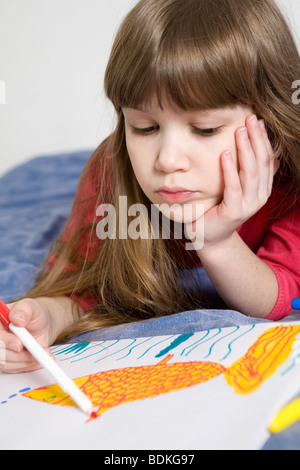 Peu de poisson dessin fille édentée souriant sur papier couché sur un tapis Banque D'Images