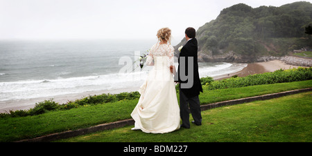 Mariée et le marié sur jour de mariage position sur pointe falaise surplombant la baie sur la péninsule de Gower Caswell Swansea au Pays de Galles du Sud Banque D'Images